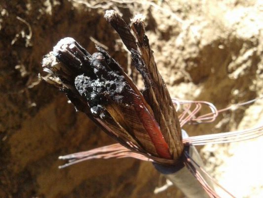 Picture of cut and burnt fiber optic cable in ground.